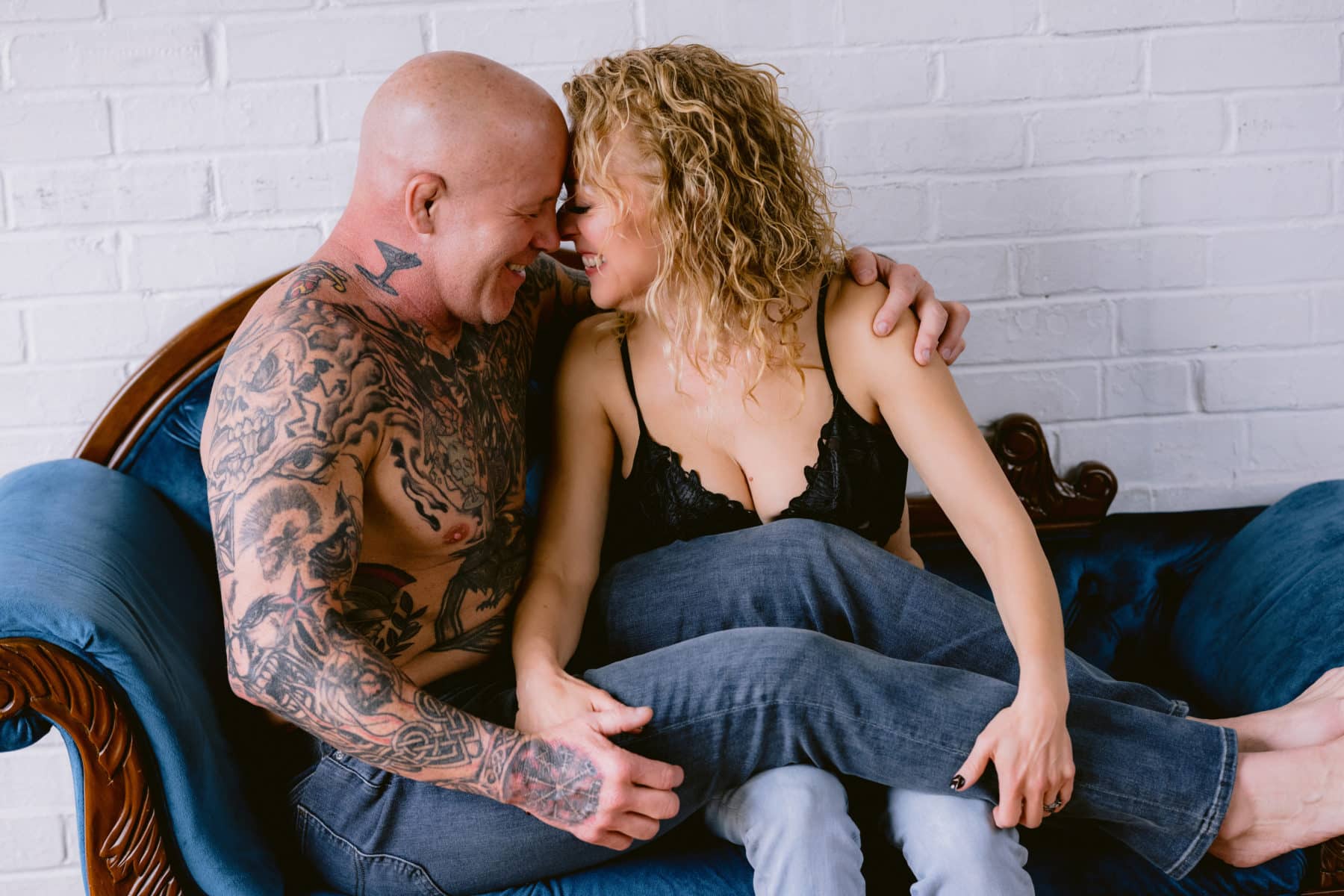 Tattooed couple snuggled on velvet couch, foreheads together, during a couples boudoir photoshoot in north wales, pennsylvania